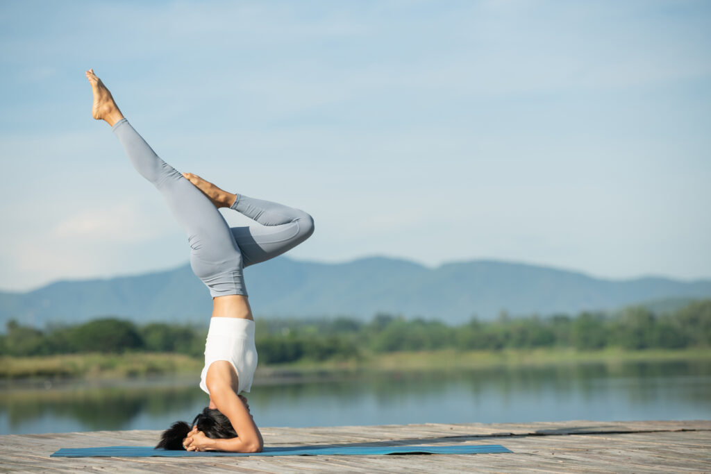 woman on a yoga mat to relax in the park. young sporty asian wom